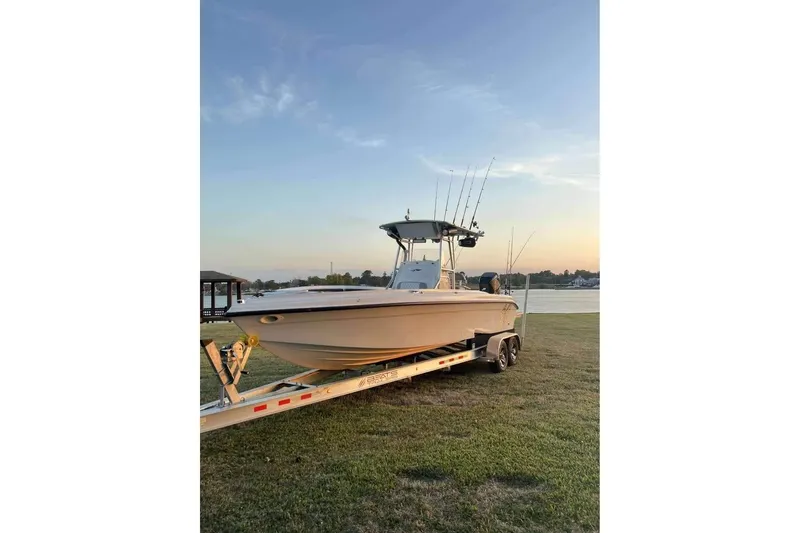 Slide: The Image of 2003 Glasstream 273 SCX boat on trailer, parked in a grassy yard under clear blue sky. - 6