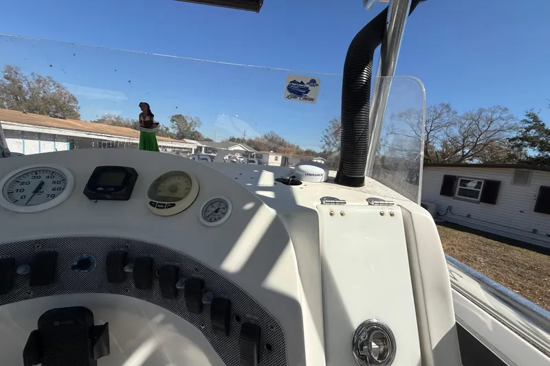 Slide: The Image of 2003 Glasstream 273 SCX boat dashboard with gauges and controls under clear blue sky. - 85