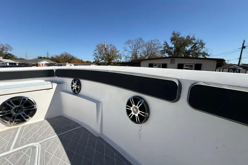 Slide: The Image of 2003 Glasstream 273 SCX boat interior with speakers and padded seating under clear blue sky. - 98