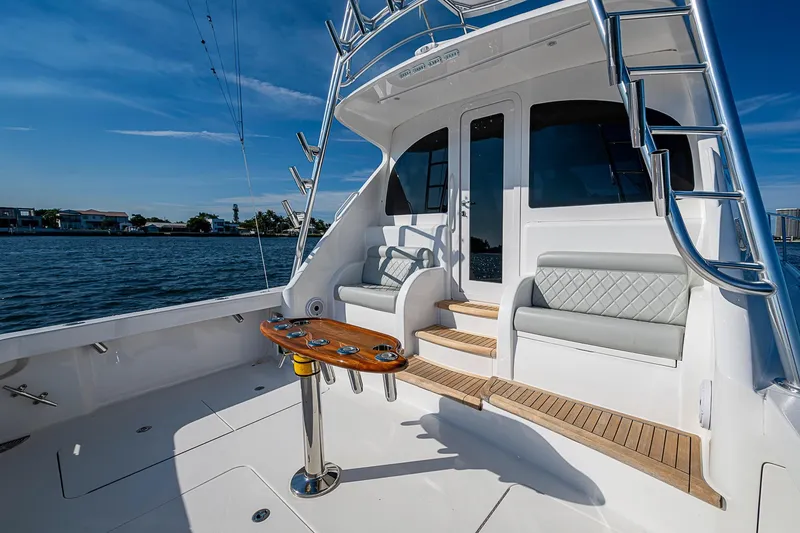 Slide: The Image of 2023 Viking 48 Sport Tower yacht deck with seating and ladder, overlooking water. - 35