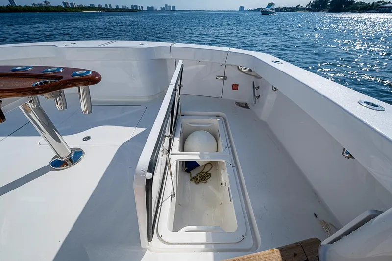 Slide: The Image of 2023 Viking 48 Sport Tower boat deck with storage compartment open, overlooking calm waters. - 42