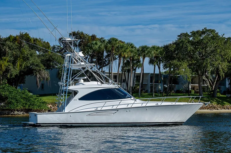 Slide: The Image of 2023 Viking 48 Sport Tower yacht cruising near palm trees and waterfront buildings. - 54