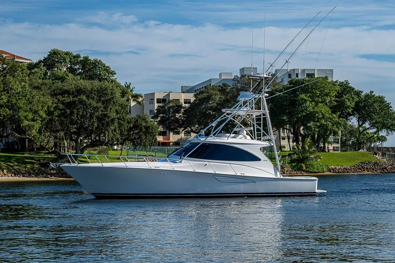 Slide: The Image of 2023 Viking 48 Sport Tower yacht on calm water, surrounded by lush greenery. - 55