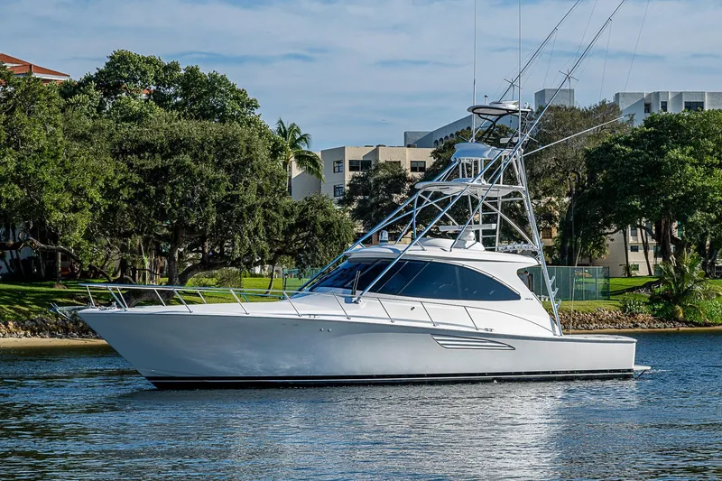 Slide: The Image of 2023 Viking 48 Sport Tower yacht on calm water, surrounded by lush greenery. - 58