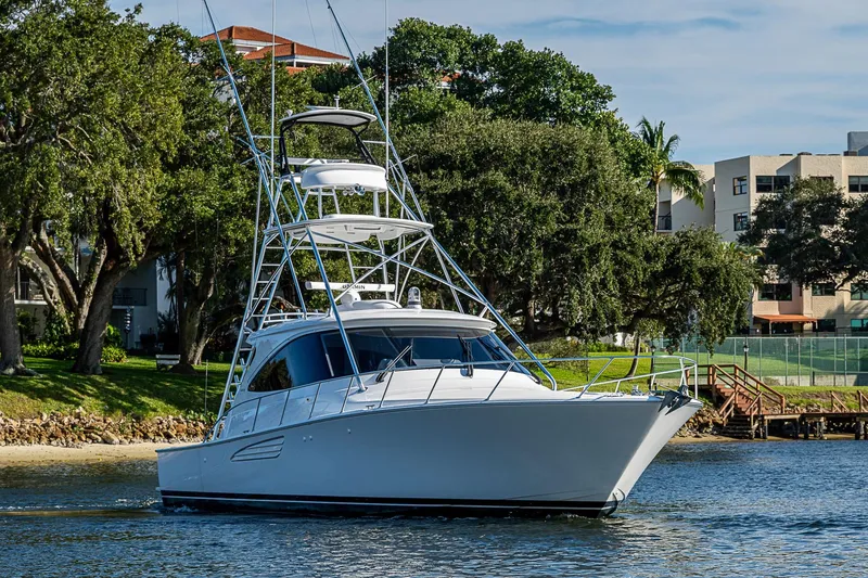 Slide: The Image of 2023 Viking 48 Sport Tower yacht cruising near a scenic shoreline. - 59