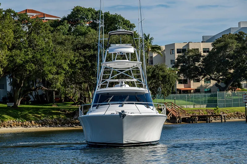 Slide: The Image of 2023 Viking 48 Sport Tower yacht cruising near shoreline with trees and buildings. - 60