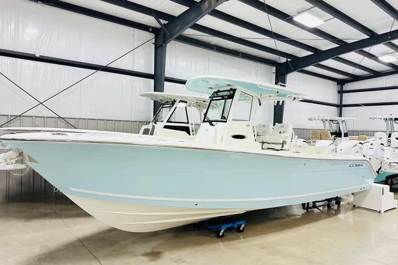 The Image of 2026 Cobia 285 Center Console boat in a showroom, light blue hull. - 1
