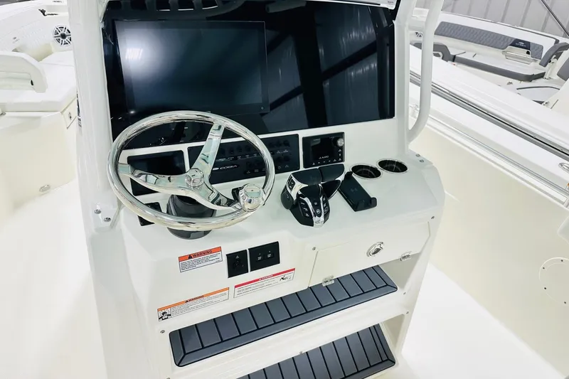 Slide: The Image of 2026 Cobia 285 Center Console boat dashboard with steering wheel and controls. - 2