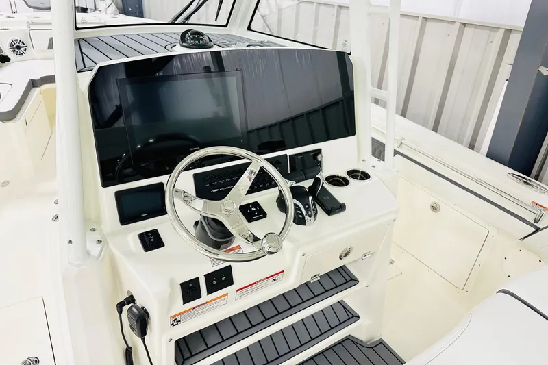 Slide: The Image of 2026 Cobia 305 Center Console boat dashboard with steering wheel and electronic controls. - 2