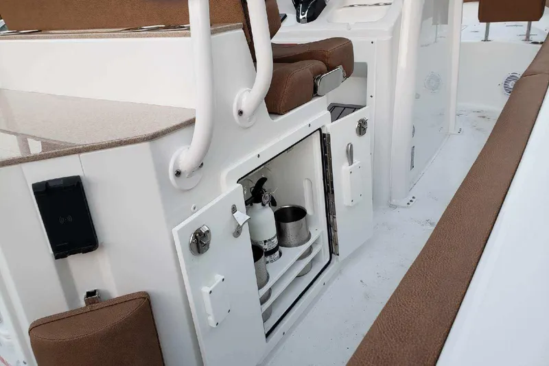 Slide: The Image of 2021 Sea Hunt Ultra 255 SE boat interior with storage compartment and brown seating. - 11