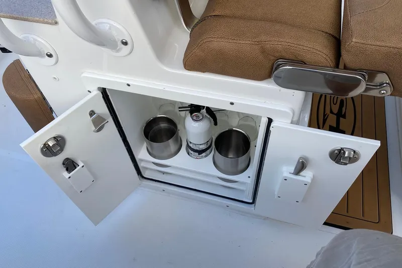 Slide: The Image of Storage compartment on a 2021 Sea Hunt Ultra 255 SE boat with fire extinguisher and cup holders. - 16