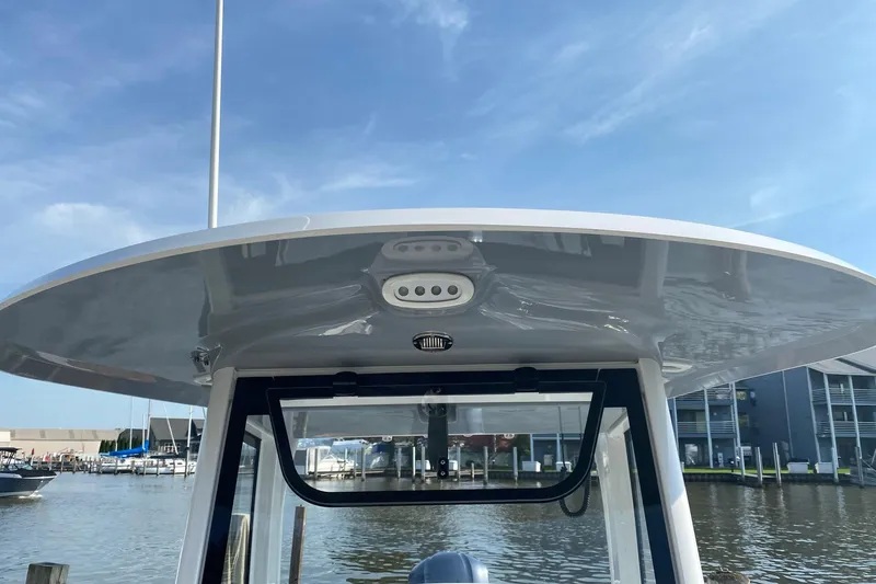Slide: The Image of 2021 Sea Hunt Ultra 255 SE boat with T-top, docked at marina under clear sky. - 19