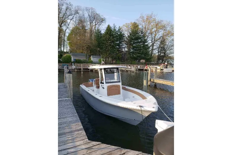 Slide: The Image of 2021 Sea Hunt Ultra 255 SE boat docked by a serene lakeside with trees in the background. - 26