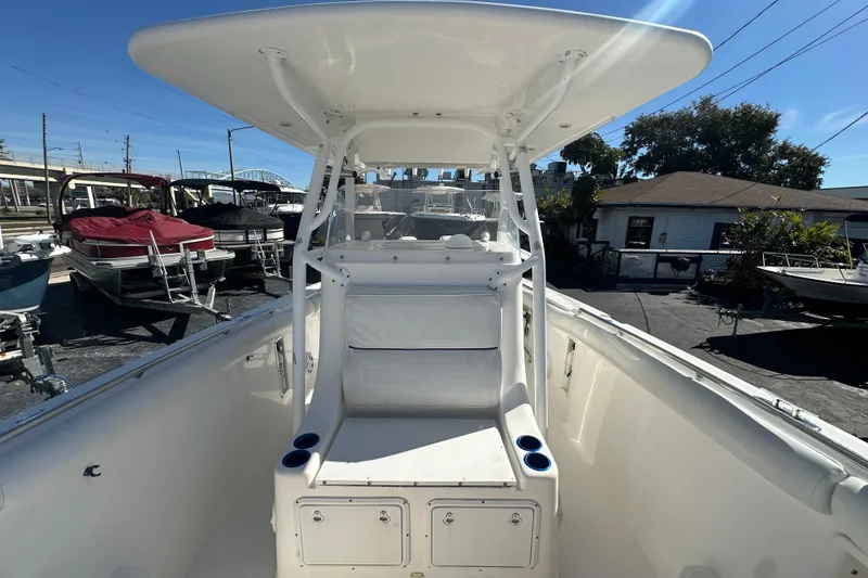 Slide: The Image of 2004 Marlago 35 FS boat interior with seating and storage, docked under clear blue sky. - 11