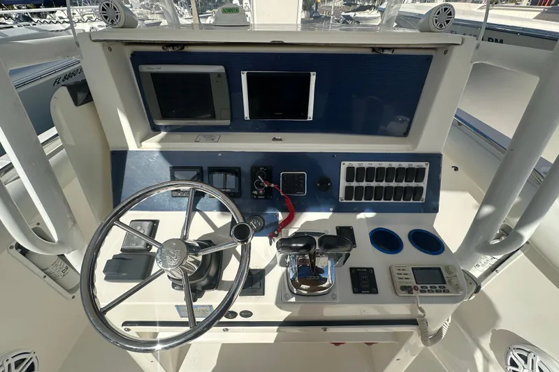 Slide: The Image of Control panel of a 2004 Marlago 35 FS boat with steering wheel and navigation equipment. - 15