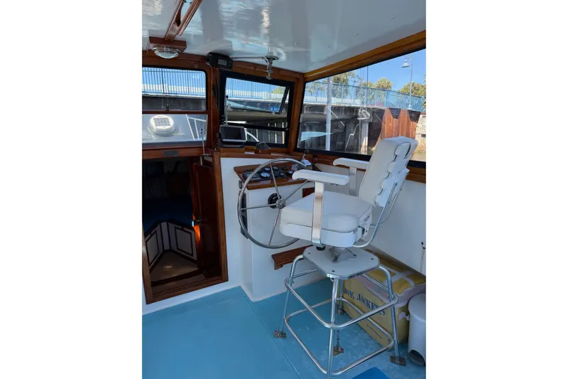 Slide: The Image of Captain's chair and helm inside a Duffy 26 boat, featuring wooden accents and large windows. - 5