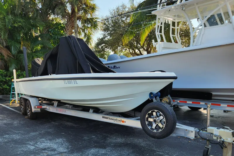 Slide: The Image of 2014 Islamorada Boatworks Morada 24 on trailer, parked in driveway near SUV. - 2