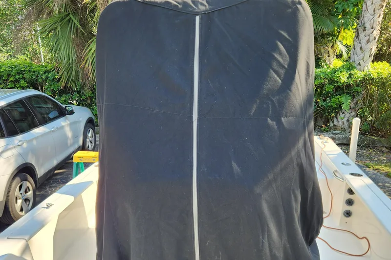 Slide: The Image of 2014 Islamorada Boatworks Morada 24 with covered outboard motor, parked near lush greenery. - 29