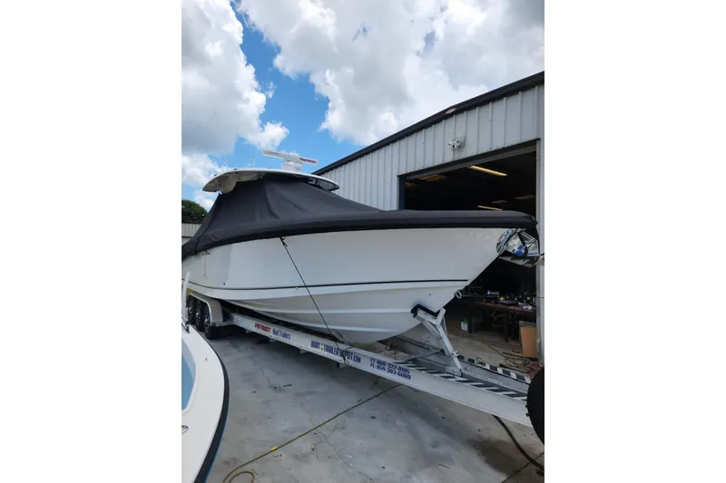 Slide: The Image of 2014 Boston Whaler 350 Outrage boat on trailer, covered, near a warehouse. - 2