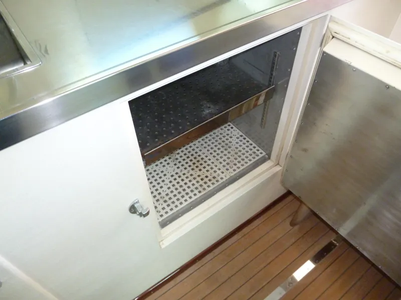 Slide: The Image of 1949 Rybovich Sport Fish interior detail with open cabinet and wooden flooring. - 34