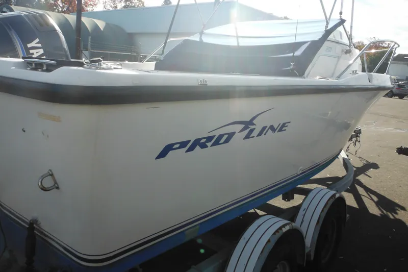 Slide: The Image of 1998 Pro-Line 201 Walkaround boat on trailer, side view with logo visible. - 10