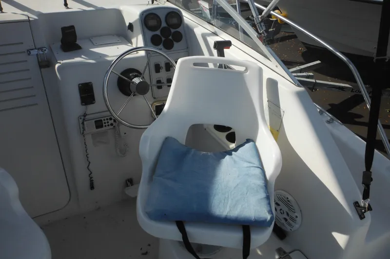 Slide: The Image of 1998 Pro-Line 201 Walkaround boat cockpit with steering wheel and cushioned seat. - 27