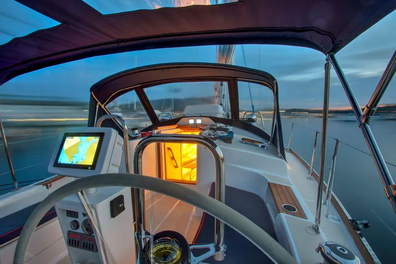 Slide: The Image of Manufacturer Provided Image: 2026 Tartan 395 yacht cockpit with navigation system, illuminated cabin, and serene waterfront view. - 7