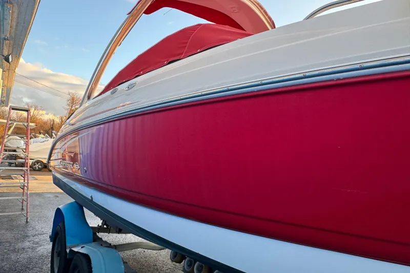 Slide: The Image of 2007 Chaparral 256 SSi boat with red and white exterior, parked on a trailer. - 49