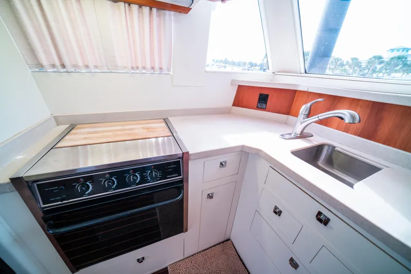 Slide: The Image of 2003 Mainship 390 Trawler kitchen with stove, sink, and white cabinetry. - 12