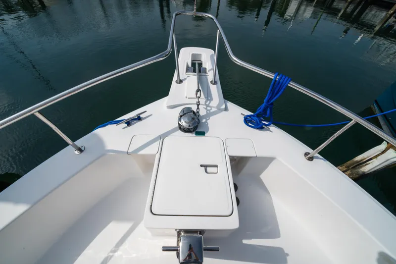 Slide: The Image of 2003 Mainship 390 Trawler bow with anchor and blue rope, docked in calm waters. - 2