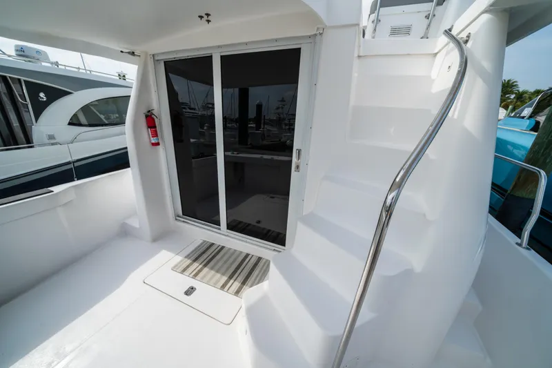 Slide: The Image of 2003 Mainship 390 Trawler deck with sliding door and staircase, featuring a fire extinguisher. - 8