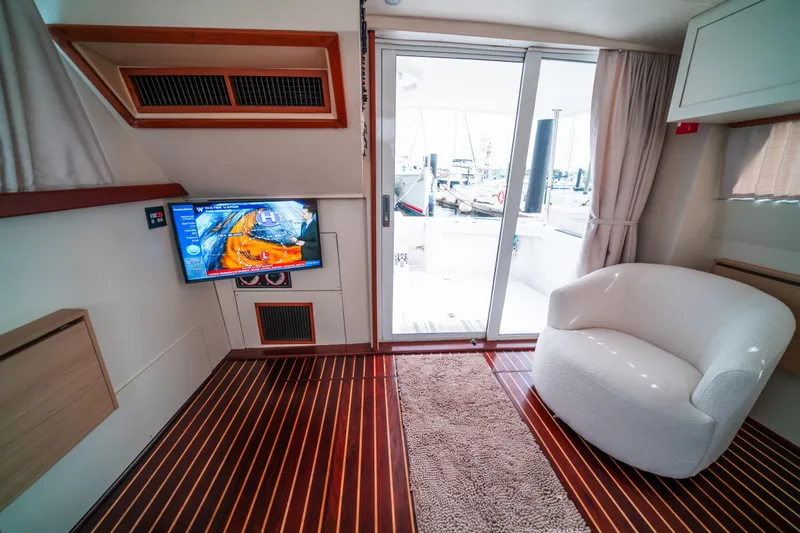 Slide: The Image of Interior of 2003 Mainship 390 Trawler with TV, white chair, and sliding glass door. - 9