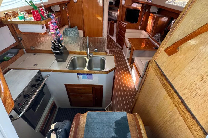 Slide: The Image of Interior of a 1997 Catalina 36 MkII sailboat, featuring a compact kitchen and cozy seating area. - 24