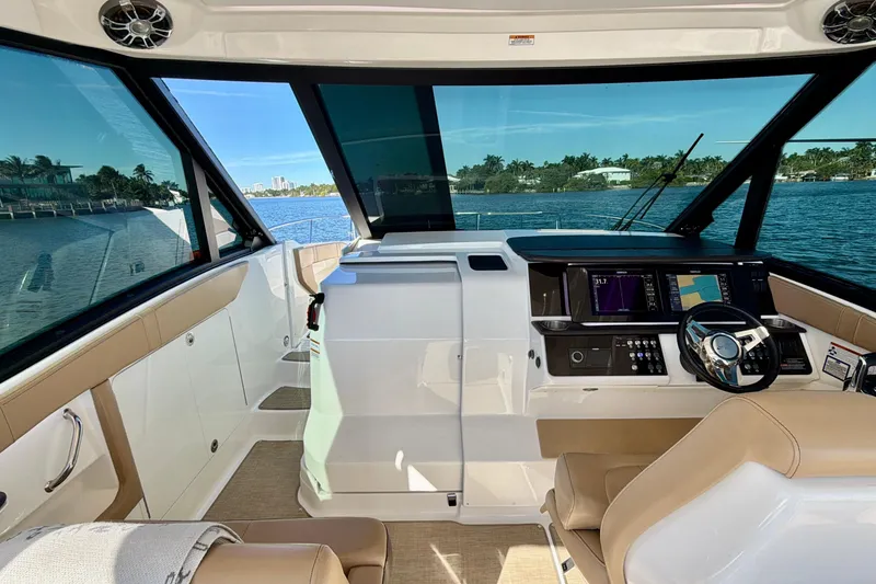 Slide: The Image of 2022 Sea Ray Sundancer 320 helm with modern controls, overlooking serene waterfront. - 25