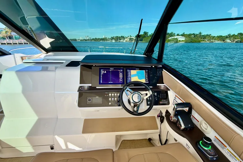 Slide: The Image of 2022 Sea Ray Sundancer 320 helm with navigation screens, steering wheel, and waterfront view. - 26