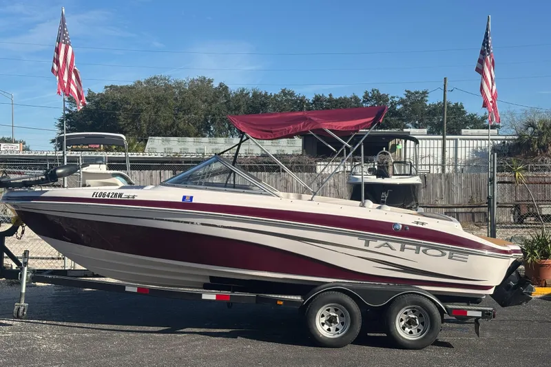 The Image of 2008 Tahoe Q6 SF boat on trailer with American flags in background. - 1