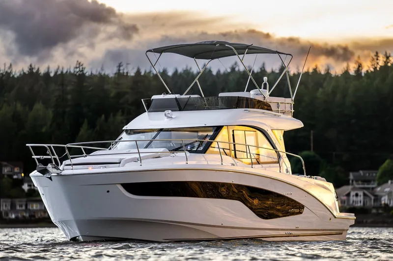 The Image of Manufacturer Provided Image: 2025 Beneteau Antares 12 Fly yacht on water at sunset, forested background. - 1