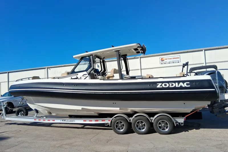 The Image of 2027 Zodiac X10CC boat on trailer, displayed outdoors under clear blue sky. - 0
