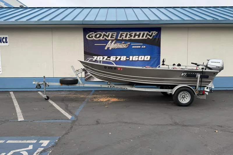 Slide: The Image of 2023 Klamath 14 Deluxe boat on trailer, parked outside "Gone Fishin'" store. - 0