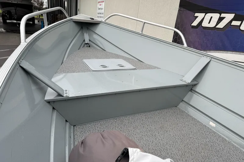 Slide: The Image of 2023 Klamath 14 Deluxe boat interior with gray carpet and storage compartment. - 13