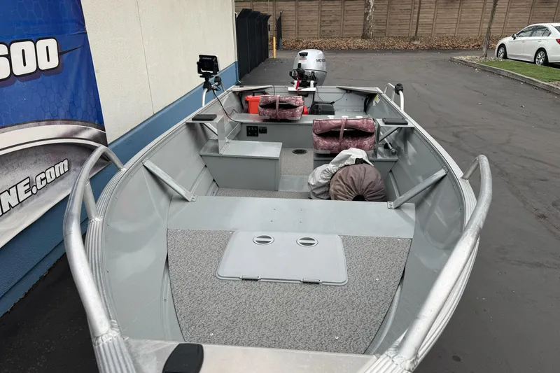Slide: The Image of 2023 Klamath 14 Deluxe boat with motor, parked outdoors, featuring spacious interior and equipment. - 2