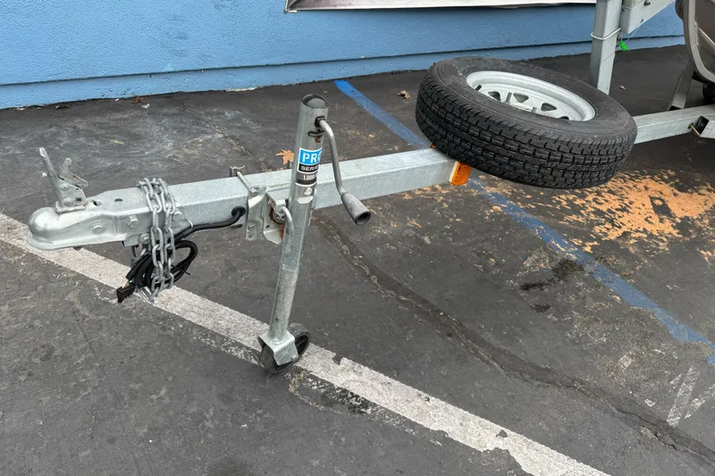 Slide: The Image of Trailer hitch and spare tire of a 2023 Klamath 14 Deluxe on pavement. - 3