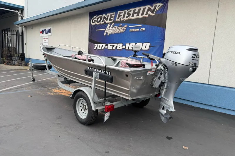 Slide: The Image of 2023 Klamath 14 Deluxe boat with Honda motor on trailer, parked outside a store. - 4