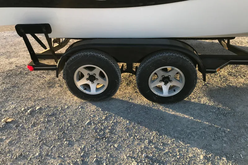 Slide: The Image of Trailer wheels of a 2001 Four Winns 200 Horizon boat on gravel. - 13