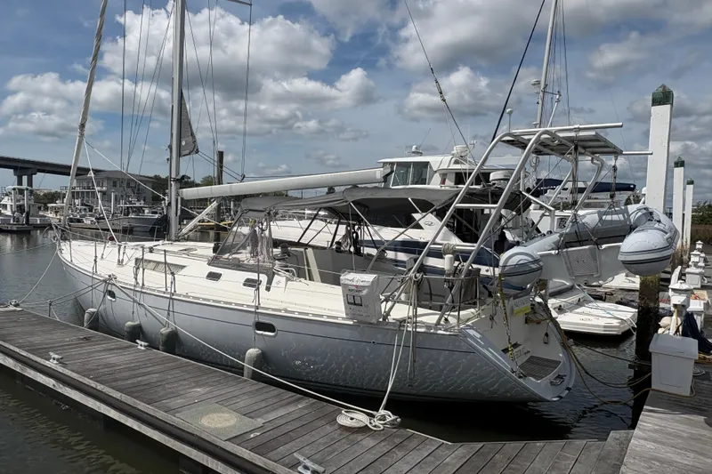 The Image of 1998 Jeanneau Sun Odyssey 45.2 sailboat docked at marina under cloudy sky. - 0