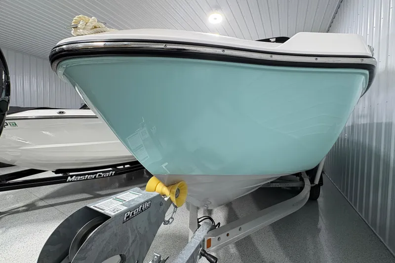Slide: The Image of 2023 Yamaha Boats 222 FSH Sport in storage, light blue hull, on trailer. - 2