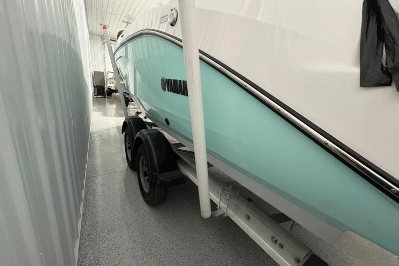 Slide: The Image of 2023 Yamaha Boats 222 FSH Sport in storage, light blue hull, on trailer. - 4