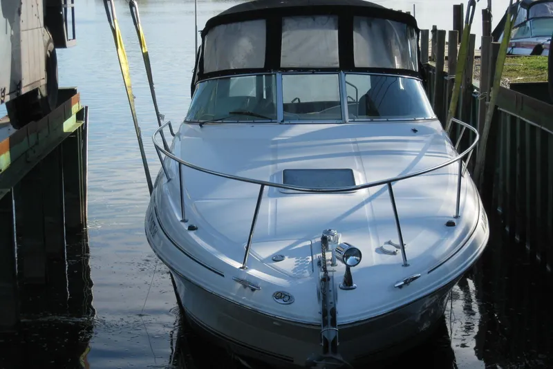 Slide: The Image of 2002 Sea Ray Sundancer 280 docked at a marina, featuring sleek design and black canopy. - 2