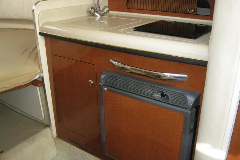 Slide: The Image of 2002 Sea Ray Sundancer 280 interior with kitchenette, featuring microwave, sink, and storage cabinets. - 33