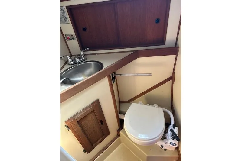Slide: The Image of 1982 Ericson 33 yacht bathroom with sink, toilet, and wooden cabinetry. - 10